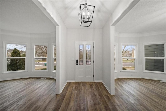 foyer entrance with crown molding, dark hardwood / wood-style floors, and a chandelier