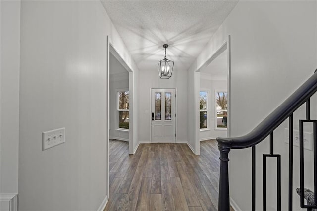 foyer with hardwood / wood-style flooring, a wealth of natural light, a chandelier, and a textured ceiling