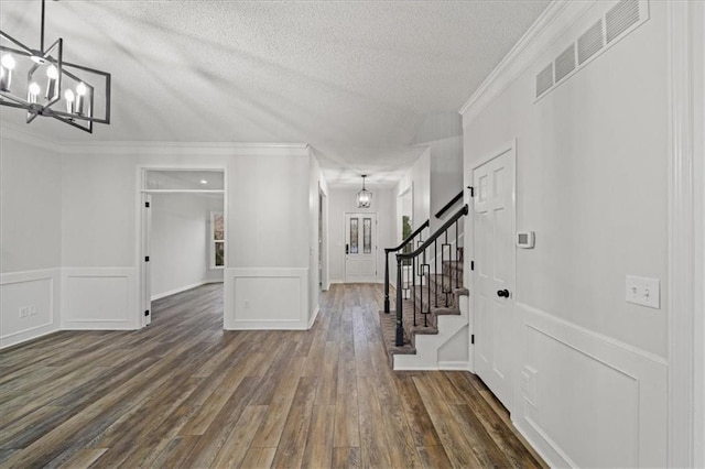 foyer featuring dark hardwood / wood-style flooring, crown molding, a notable chandelier, and a textured ceiling