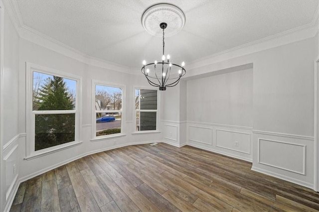 unfurnished dining area with an inviting chandelier, ornamental molding, dark hardwood / wood-style floors, and a textured ceiling