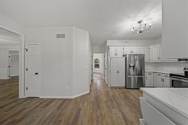 kitchen with appliances with stainless steel finishes, light stone countertops, wood-type flooring, and white cabinets