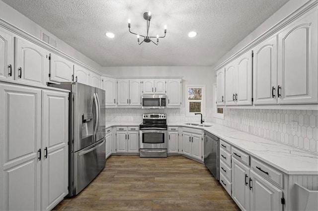 kitchen featuring tasteful backsplash, white cabinetry, sink, stainless steel appliances, and dark wood-type flooring