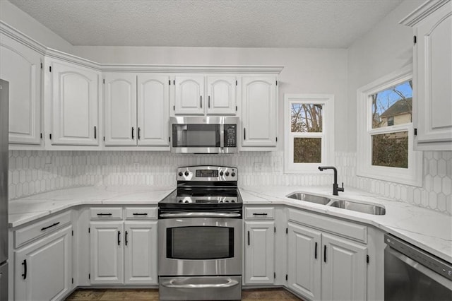 kitchen with sink, white cabinetry, stainless steel appliances, a textured ceiling, and decorative backsplash