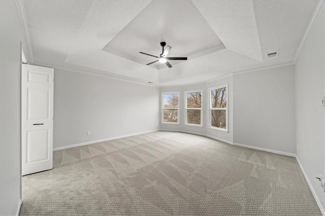 carpeted empty room featuring a raised ceiling, crown molding, and ceiling fan