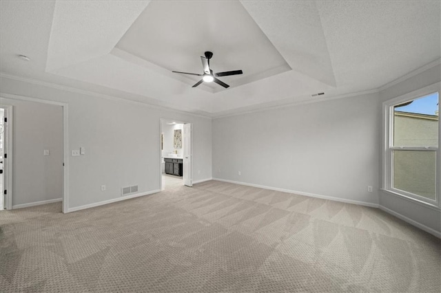 unfurnished living room featuring light carpet, a tray ceiling, crown molding, and ceiling fan