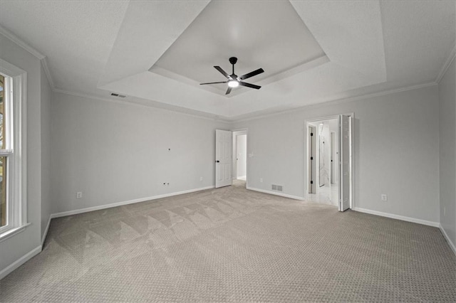 carpeted spare room with crown molding, a raised ceiling, and ceiling fan