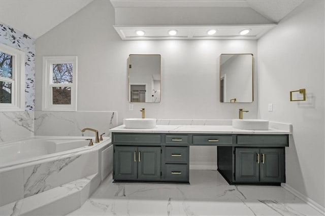 bathroom featuring vanity, vaulted ceiling, and tiled tub