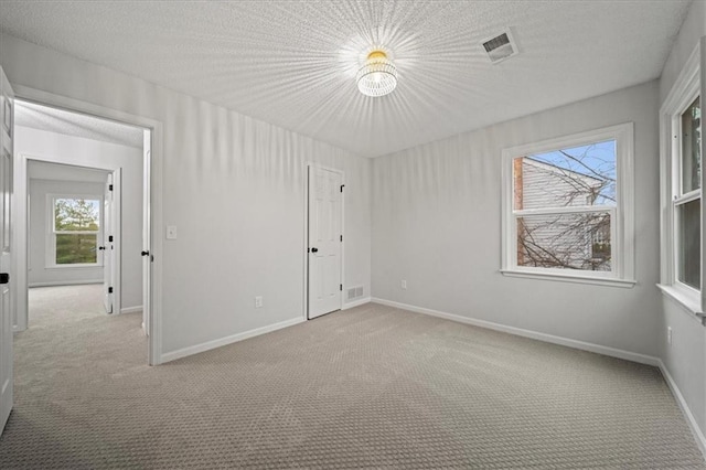 empty room featuring light colored carpet and a textured ceiling