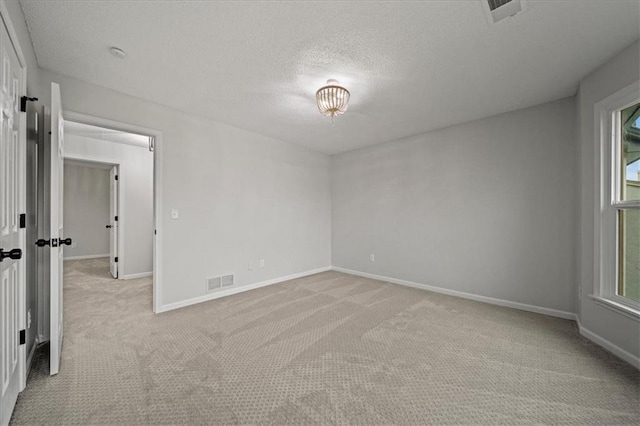 empty room featuring light colored carpet and a textured ceiling