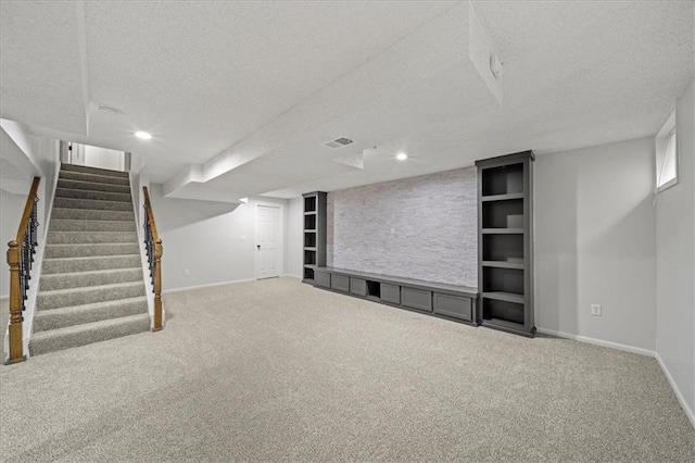 basement with carpet flooring, a textured ceiling, and built in shelves