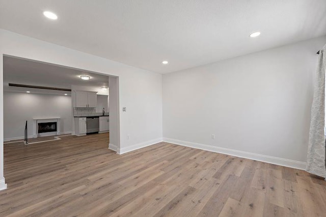 unfurnished living room with sink and light wood-type flooring