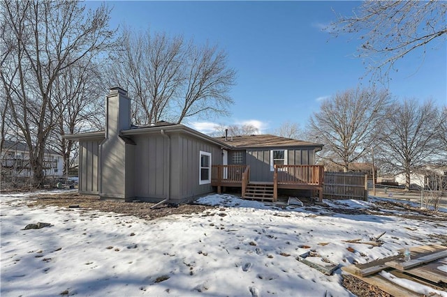 snow covered back of property featuring a wooden deck