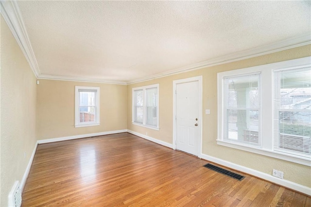 empty room with crown molding, hardwood / wood-style floors, and a textured ceiling