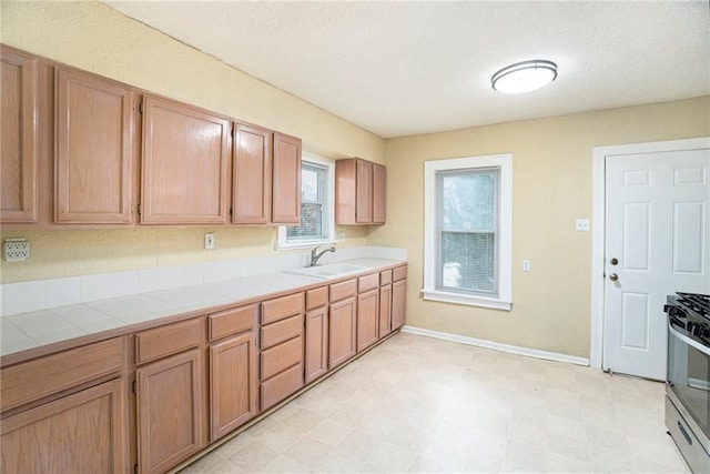 kitchen featuring sink, tile countertops, and gas stove