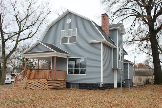 rear view of house featuring central AC and a lawn