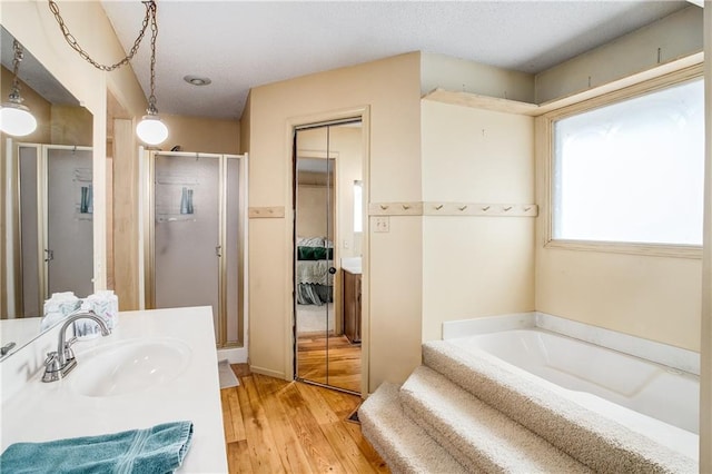 bathroom featuring hardwood / wood-style flooring, vanity, and separate shower and tub