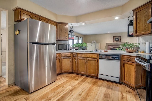 kitchen with sink, decorative light fixtures, light hardwood / wood-style floors, and appliances with stainless steel finishes