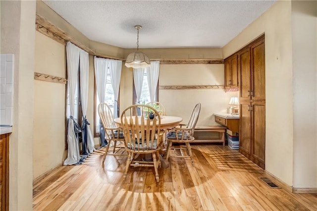 dining room with light hardwood / wood-style flooring and a textured ceiling