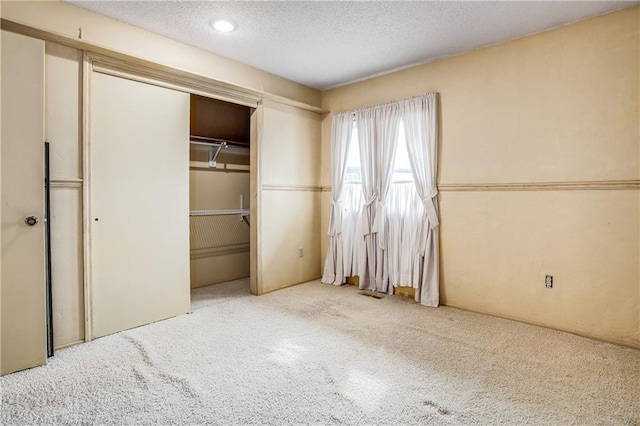 unfurnished bedroom with a closet, a textured ceiling, and carpet