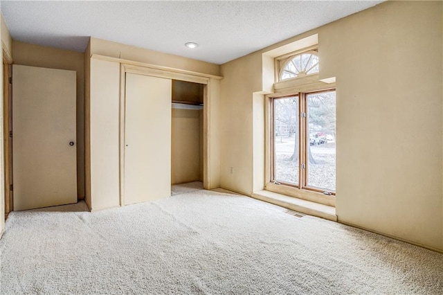 unfurnished bedroom featuring carpet floors, a closet, and a textured ceiling