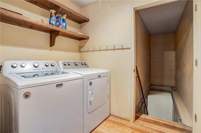 laundry room with washing machine and clothes dryer and light hardwood / wood-style floors