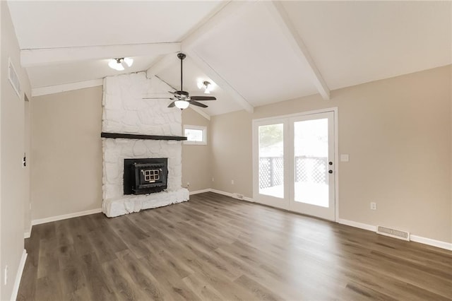 unfurnished living room featuring a stone fireplace, lofted ceiling with beams, dark hardwood / wood-style floors, and ceiling fan