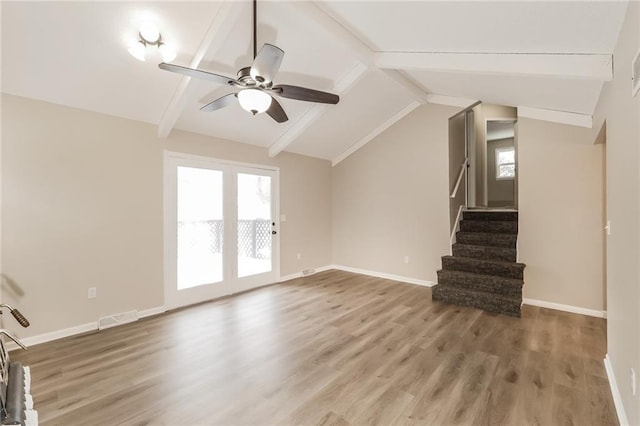 unfurnished living room with hardwood / wood-style flooring, ceiling fan, lofted ceiling with beams, and a wealth of natural light