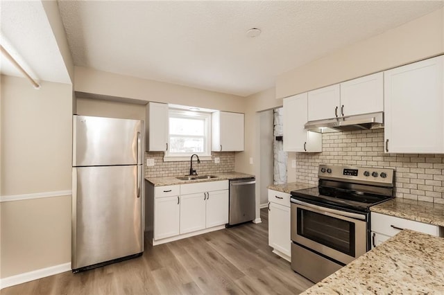 kitchen with light stone countertops, appliances with stainless steel finishes, sink, and white cabinets