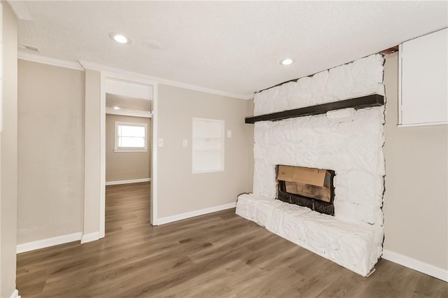 sitting room featuring a stone fireplace, dark wood-type flooring, and ornamental molding