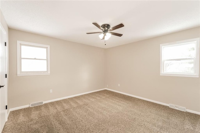 carpeted empty room with a wealth of natural light and ceiling fan