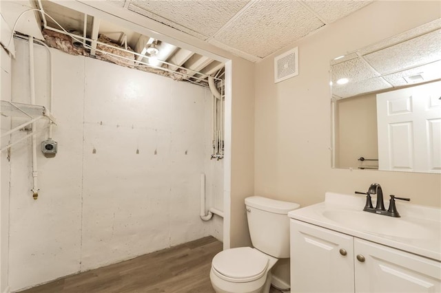 bathroom featuring vanity, wood-type flooring, a paneled ceiling, and toilet