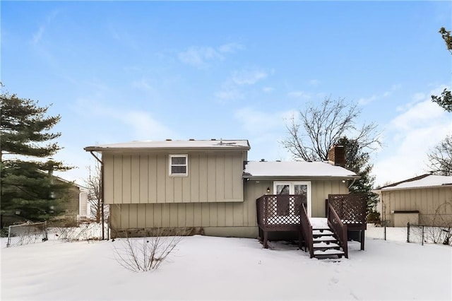 snow covered back of property featuring a deck