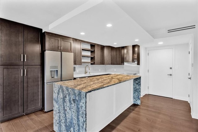 kitchen with light stone counters, hardwood / wood-style floors, stainless steel fridge with ice dispenser, and a kitchen island