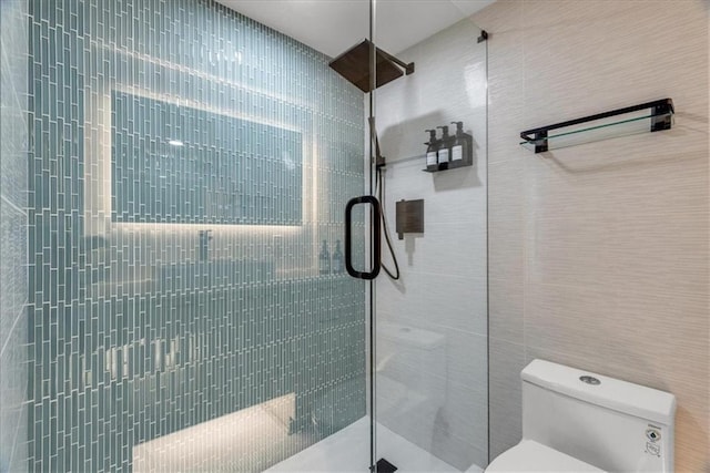 bathroom featuring a shower with shower door and toilet