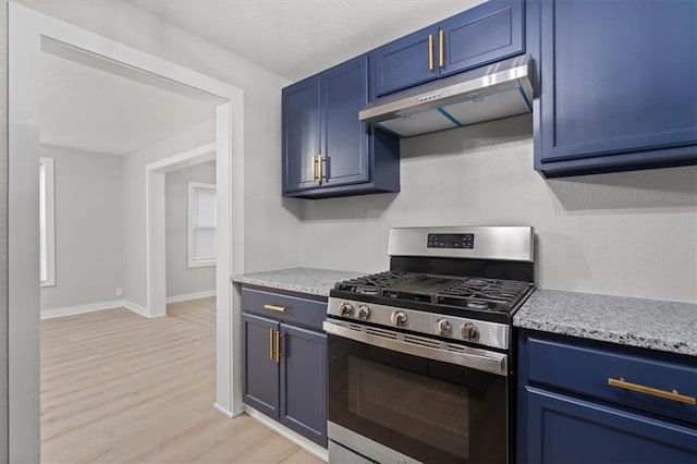 kitchen featuring blue cabinets, stainless steel range with gas stovetop, light stone counters, and light hardwood / wood-style flooring