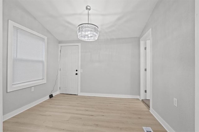 unfurnished dining area featuring lofted ceiling, a chandelier, and light hardwood / wood-style flooring