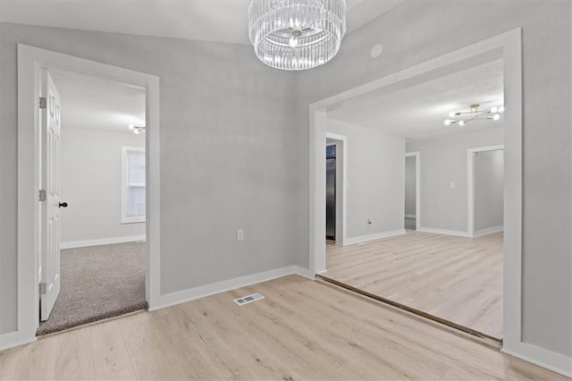 empty room featuring an inviting chandelier and light wood-type flooring