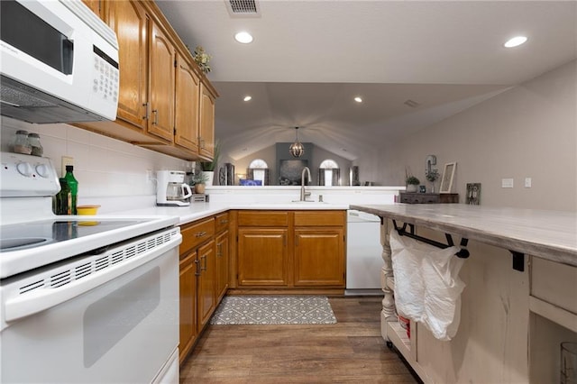 kitchen featuring vaulted ceiling, dark hardwood / wood-style floors, sink, kitchen peninsula, and white appliances