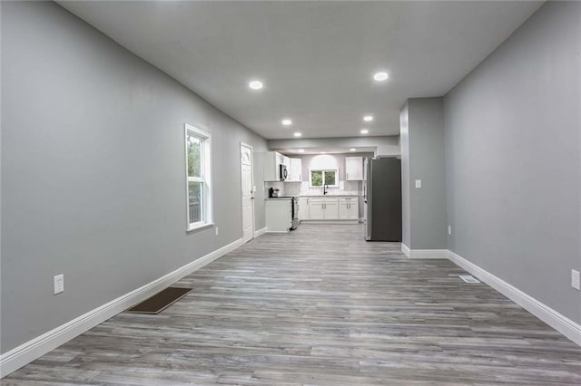 unfurnished living room with sink and light hardwood / wood-style floors