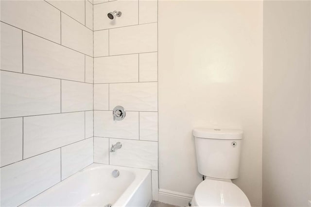 bathroom with tiled shower / bath combo and toilet