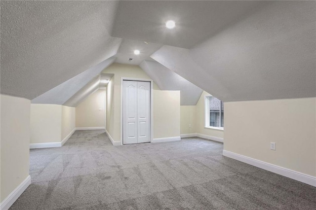 additional living space featuring light colored carpet, lofted ceiling, and a textured ceiling