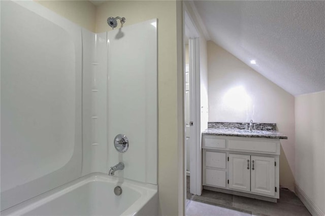 bathroom featuring tile patterned floors, lofted ceiling, a textured ceiling, vanity, and shower / washtub combination