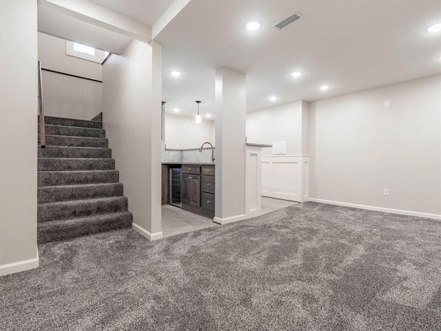 unfurnished living room with light carpet, wet bar, and beverage cooler