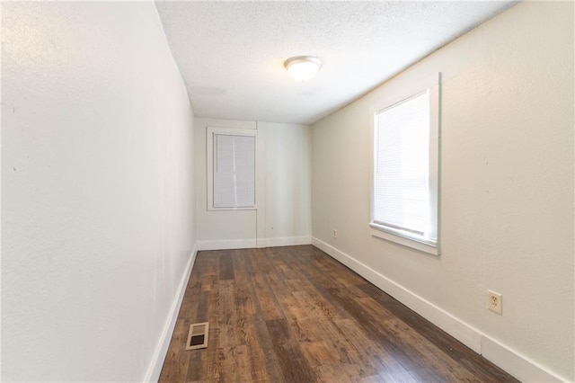 spare room with dark hardwood / wood-style floors and a textured ceiling