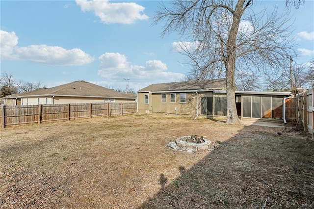 back of house featuring an outdoor fire pit, a sunroom, and a lawn