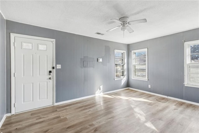 foyer entrance with light hardwood / wood-style flooring, a textured ceiling, plenty of natural light, and ceiling fan