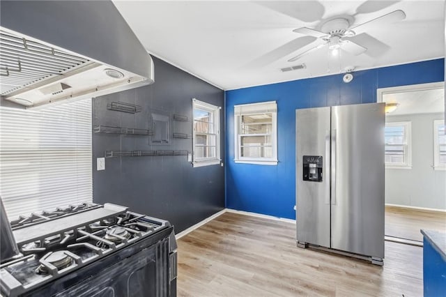 kitchen with stainless steel fridge, island exhaust hood, ceiling fan, light hardwood / wood-style floors, and black gas stove