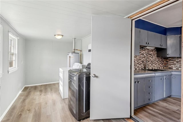 kitchen with washer and clothes dryer, light hardwood / wood-style flooring, water heater, gray cabinets, and decorative backsplash