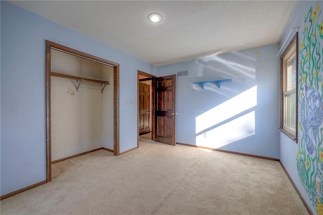 unfurnished bedroom with light colored carpet, a closet, and a textured ceiling