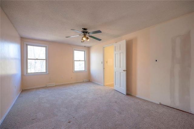 carpeted spare room featuring ceiling fan and a textured ceiling